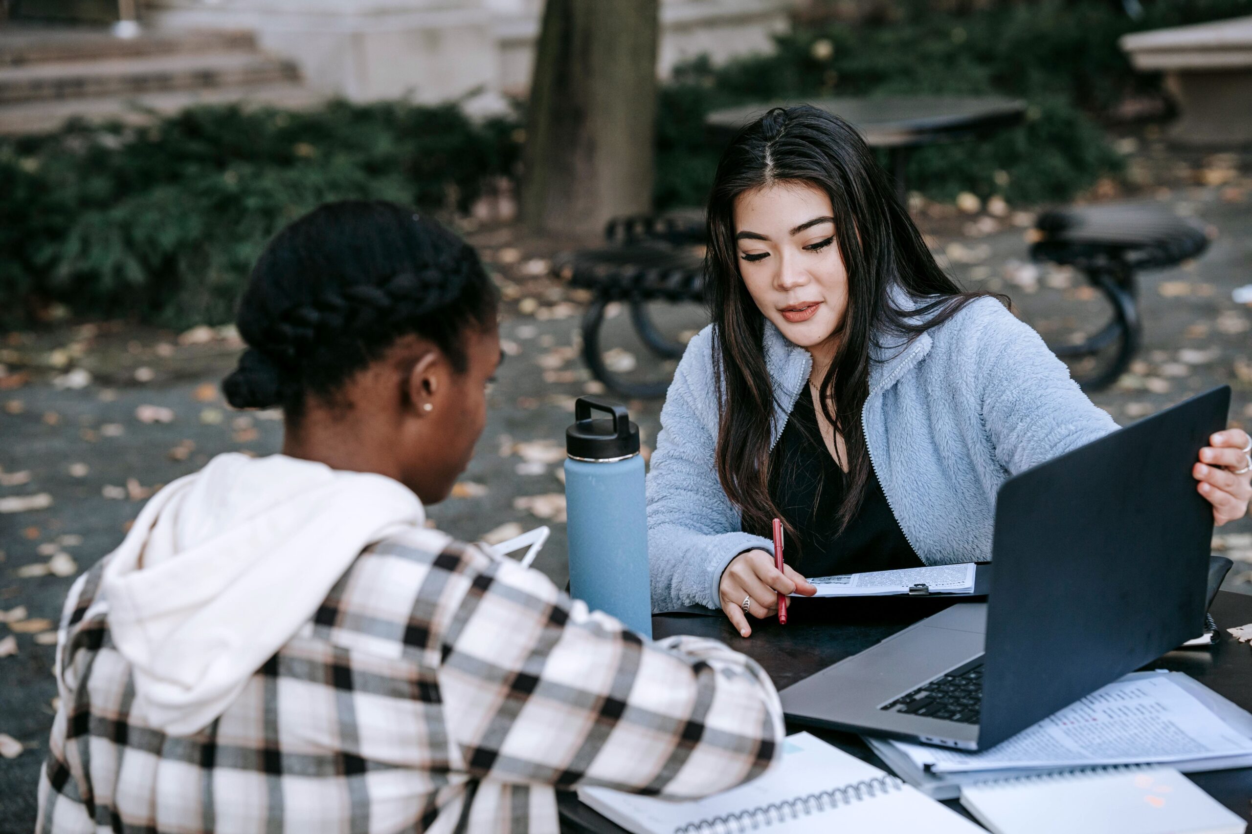 Zwei junge Frauen sitzen am Tisch auf dem ein Laptop steht
